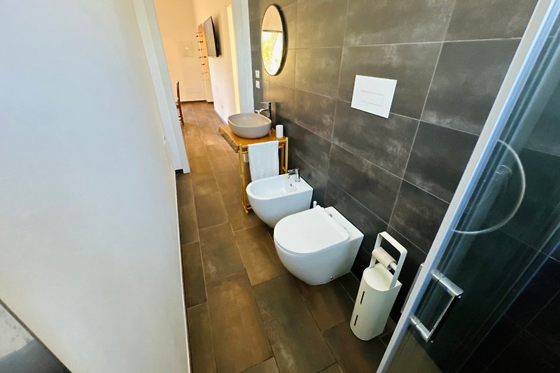 Modernes Badezimmer mit lila Akzenten, Toilette, Waschbecken und Armaturen.