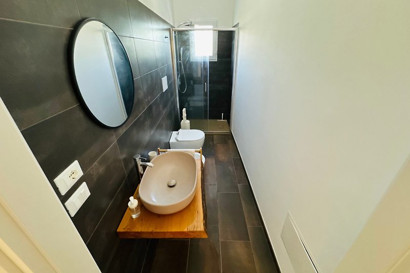 Modernes Badezimmer mit Spiegel, Waschbecken und Toilette.