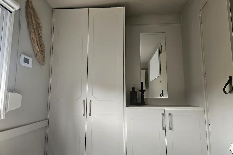 Moderne Badezimmereinrichtung mit Spiegel, Schrank und Armaturen.