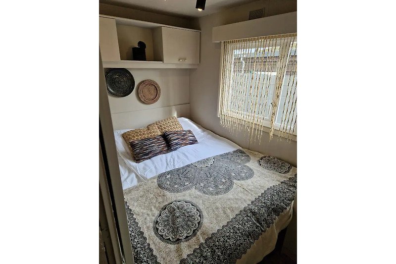 Schlafzimmer mit Bett, Kissen, Holz und Fenster.