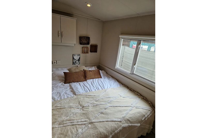 Gemütliches Schlafzimmer mit Holzbett, Fenster und Lampen.