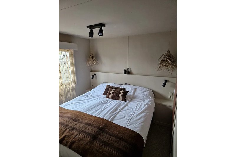Gemütliches Schlafzimmer mit Holzbett und Lampen.