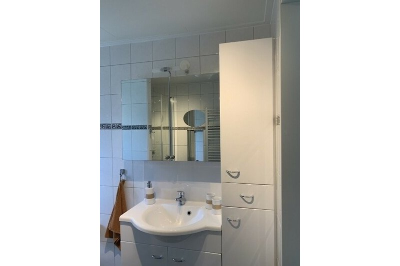 Modernes Badezimmer mit Spiegelschrank, Waschbecken und weiteren Schränken