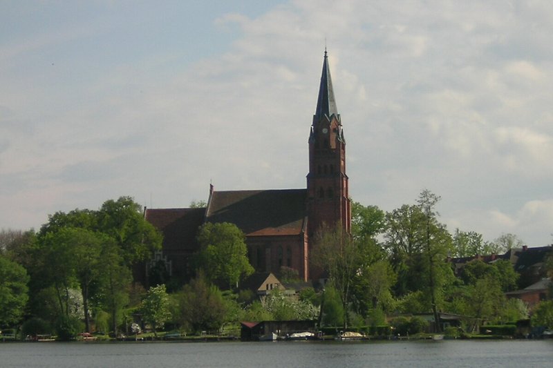 Kirche am Seeufer mit mittelalterlicher Architektur und Turm.