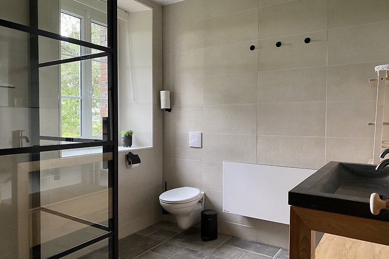 Modernes Badezimmer mit Glasdusche und Holzdetails.
