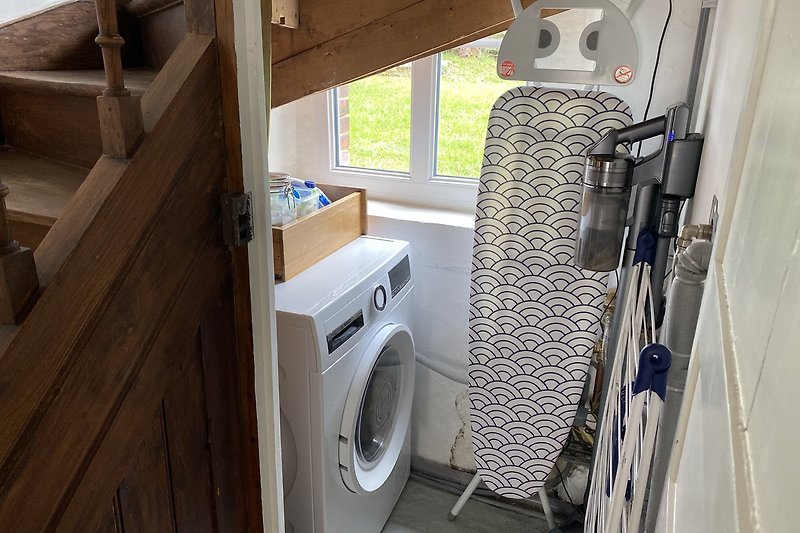 Moderne Waschküche mit Fenster, Waschmaschine und Trockner.