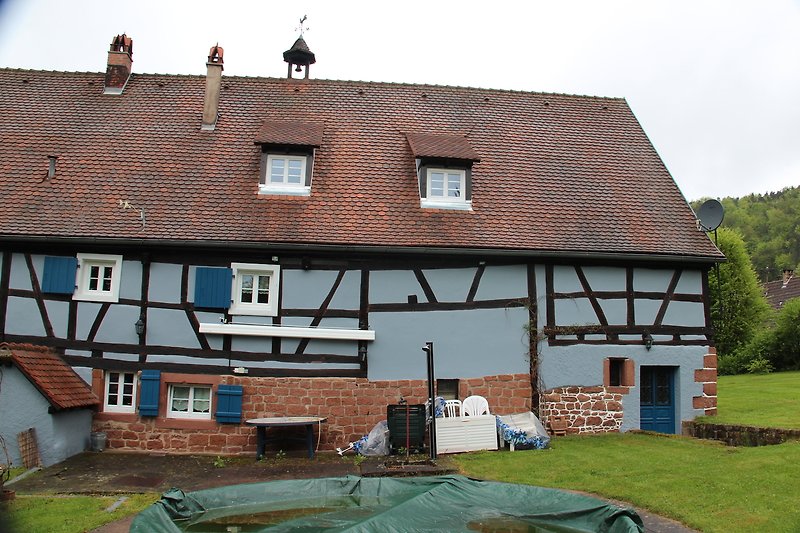 Traditionelles Haus mit rotem Ziegeldach und grünem Garten.