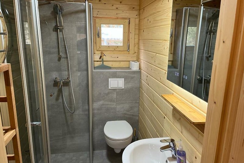 Modernes Badezimmer mit Dusche, Spiegel und Toilette.