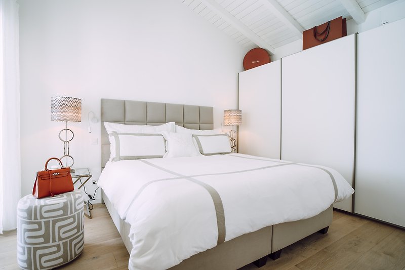 Elegantes Schlafzimmer mit hochwertigem Bett und stilvoller Beleuchtung.
