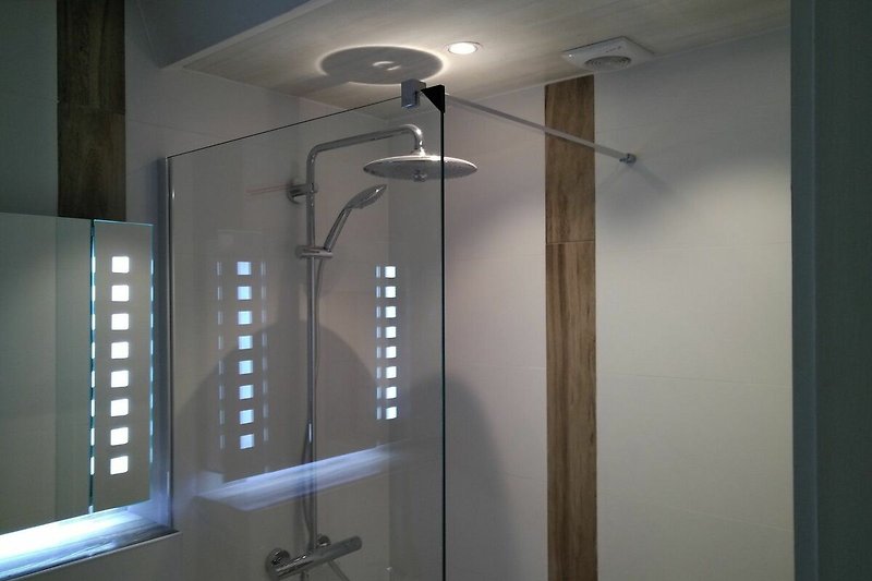 Badezimmer mit Dusche, Lampe und Glaswand.