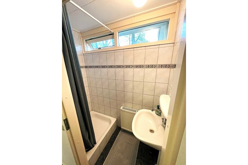 Modernes Badezimmer mit Holzakzenten und Spiegel.