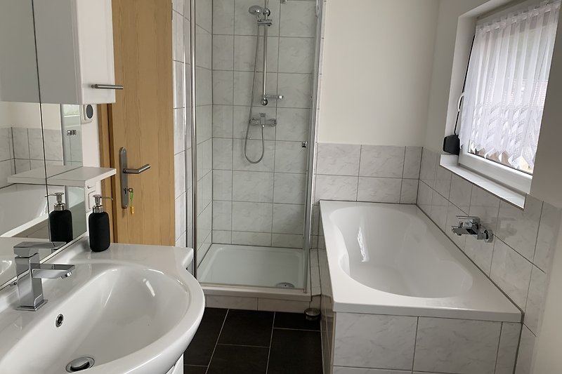Modernes Badezimmer mit Badewanne, Dusche und Spiegel.