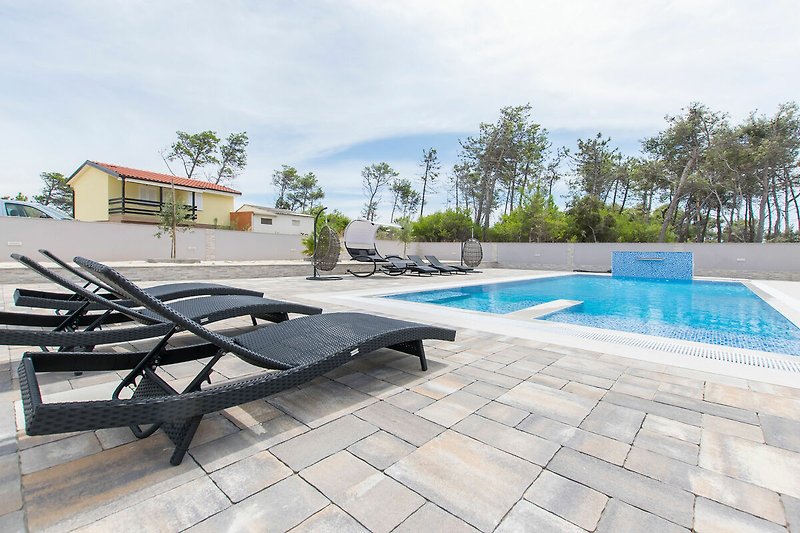 Luxuriöses Ferienhaus mit Pool und Palmen am Wasser.