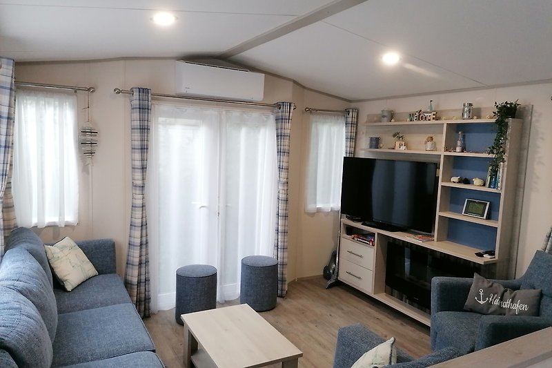 Wohnzimmer mit bequemer Couch, Fernseher und Klimaanlage