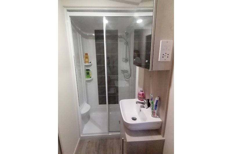 Modernes Badezimmer mit Spiegel, Waschbecken und Armatur.