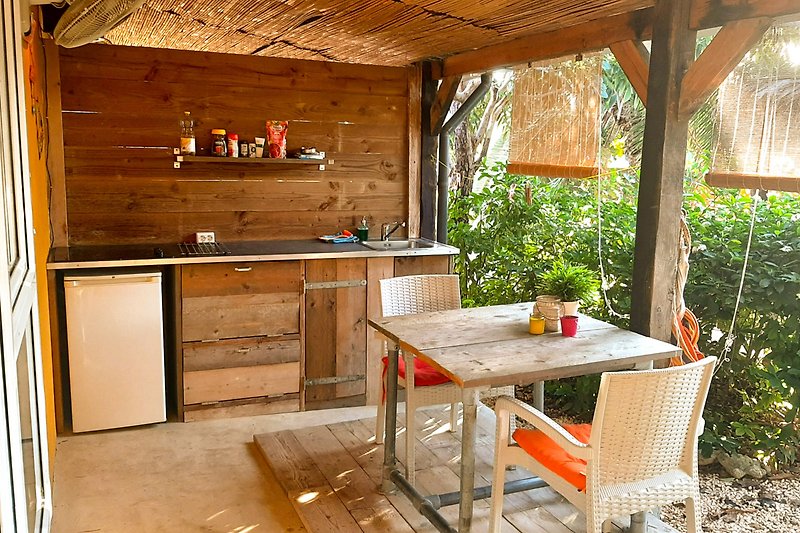 Küche mit Holzmöbeln, Esstisch, Stühlen und Pflanze.