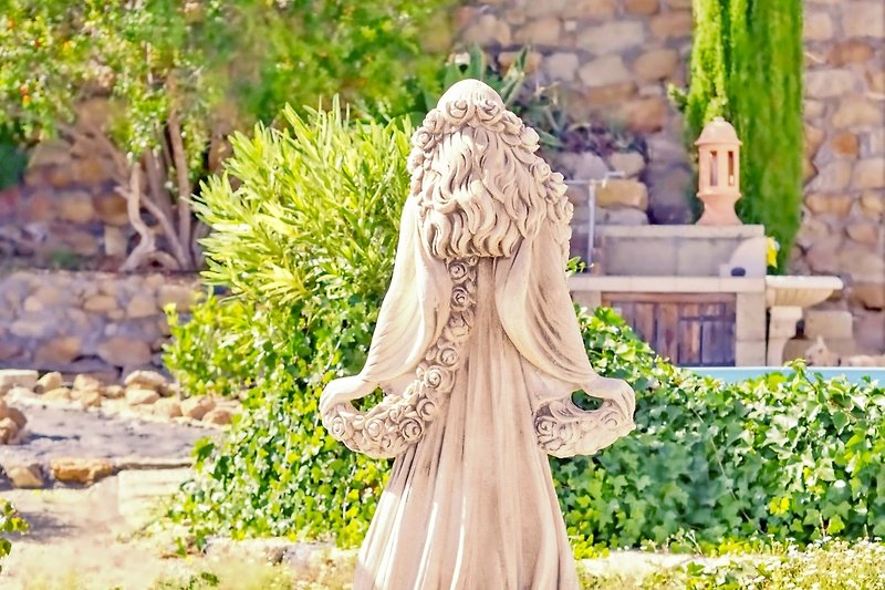 Skulptur und Statue im Garten mit Pflanzen