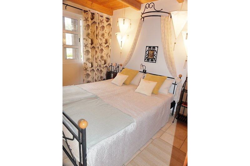Schlafzimmer mit elegantem Bett, stilvoller Beleuchtung und Fenster.