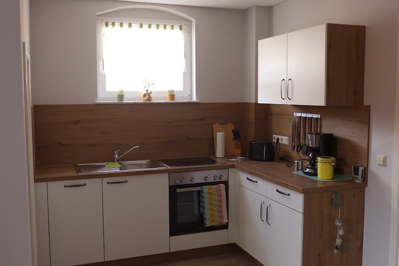 Moderne Küche mit Holzdetails und Küchengeräten.