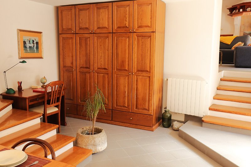 Wohnzimmer mit Holzmöbeln, Schrank, Pflanze und Bilderrahmen.