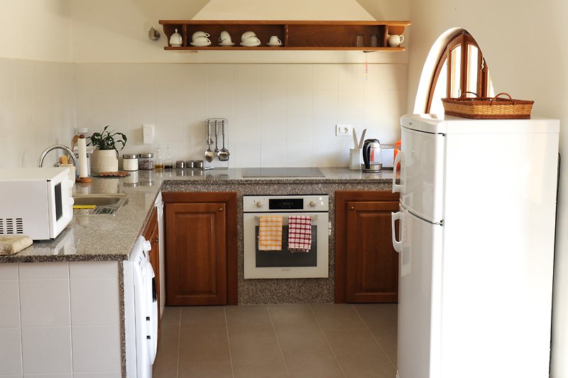 Moderne Küche mit braunen Schränken, Küchengeräten und Holzarbeitsplatte.
