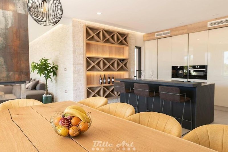 Moderne Küche mit eleganten Schränken und Holztisch.