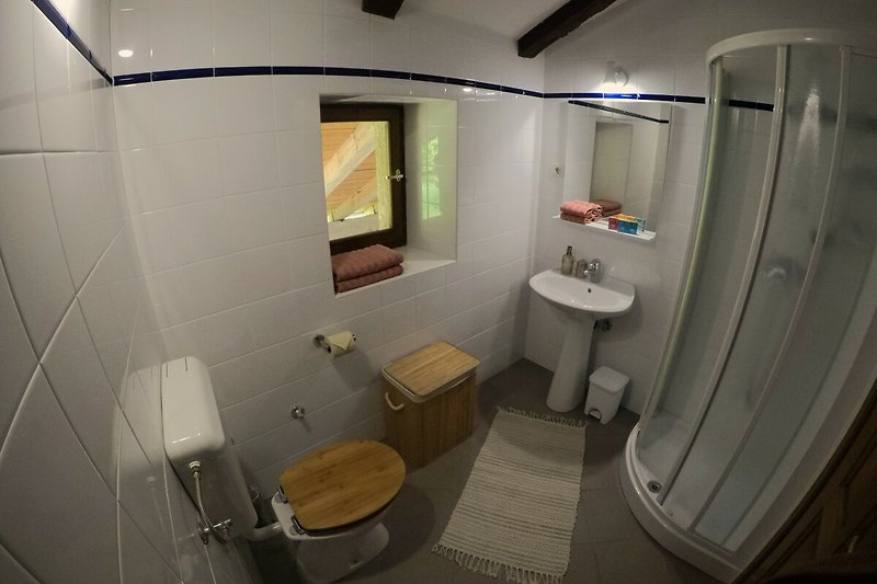 Modernes Badezimmer mit Spiegel, Armatur und lila Akzenten.