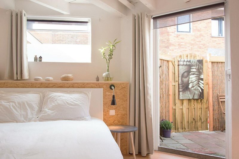 Schlafzimmer mit Holzmöbeln, gemütlichem Bett, Fenster und Lampenschirm.