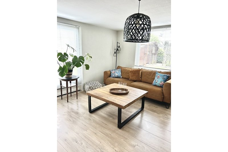 Wohnzimmer mit Couch, Tisch, Pflanze und Bilderrahmen.