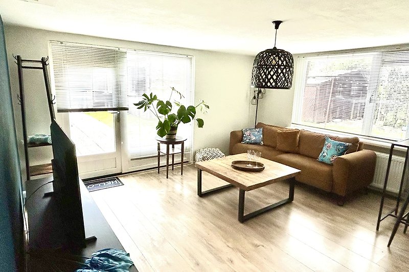 Wohnzimmer mit Holzmöbeln, Couch, Tisch und Pflanze.