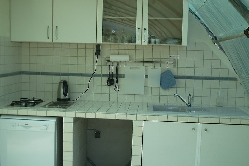 Moderne Küche mit Gasofen, Spüle und Fenster.