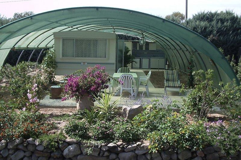 Haus mit blühendem Garten, Zelt und Stühlen.