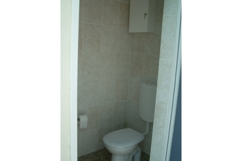 Toilette mit Holztoilettenbrille und Tür.