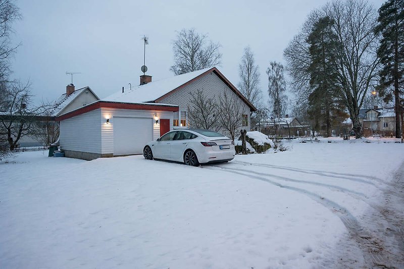 Winterlandschaft mit Auto, Reifen, Haus und Schnee.