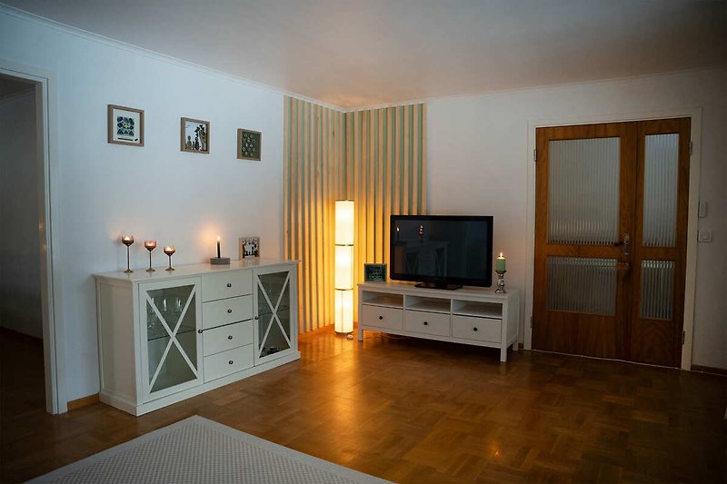 Wohnzimmer mit Fernseher, Pflanze und Holzmöbeln.