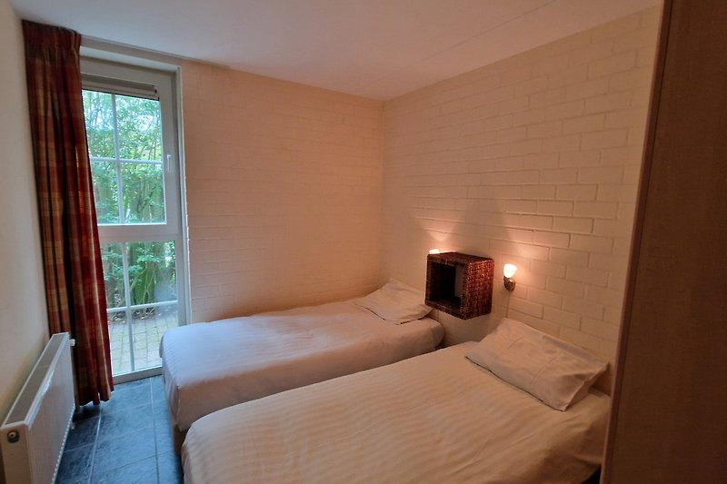 Gemütliches Schlafzimmer mit Holzmöbeln, Bett, Lampen und Fenster.