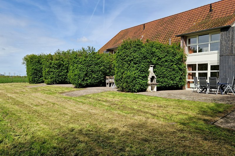 Ländliches Haus mit grünem Garten und blauem Himmel.