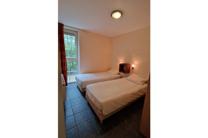 Schlafzimmer mit bequemem Bett, Holzmöbeln und Lampen.