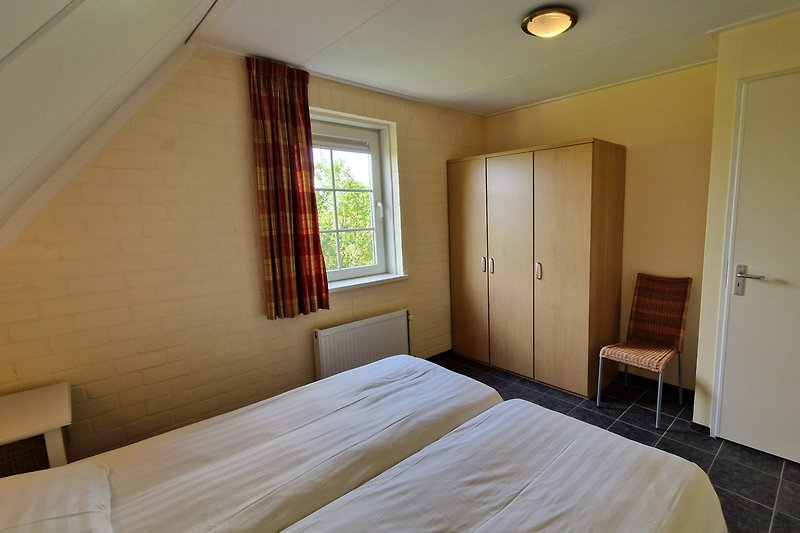 Modernes Schlafzimmer mit stilvollem Bett, Fenster und Lampen.