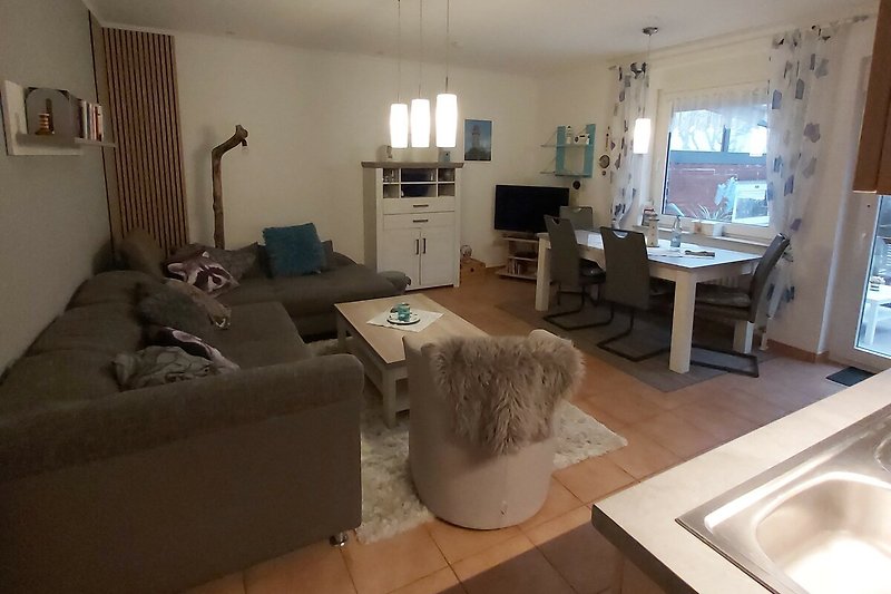 Wohnzimmer mit Couch, Tisch, Fernseher und Lampe.