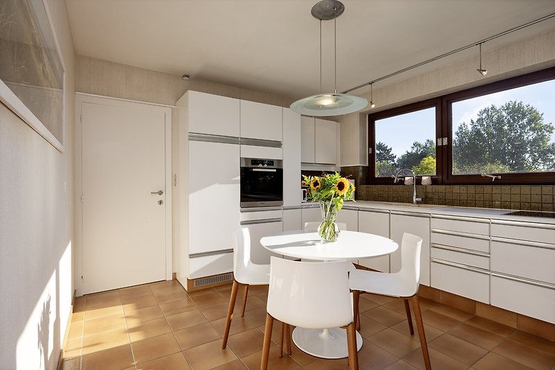Moderne Küche mit eleganten Schränken, Fenster und Holzboden.