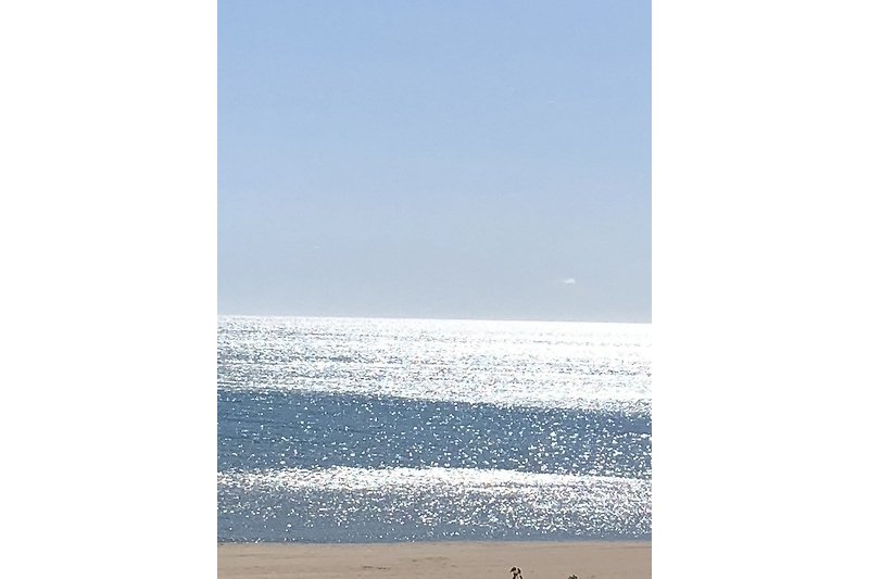 Strand mit blauem Himmel und Wellen.