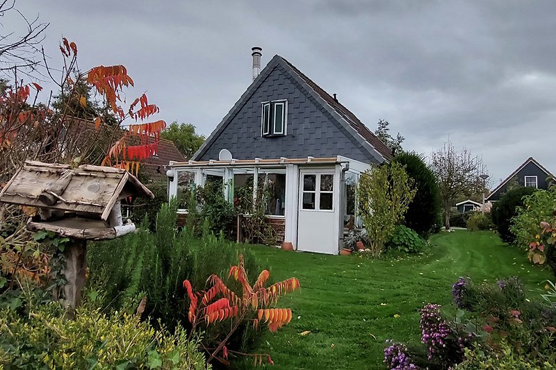 Gemütliches Haus mit blühendem Garten und grüner Wiese.