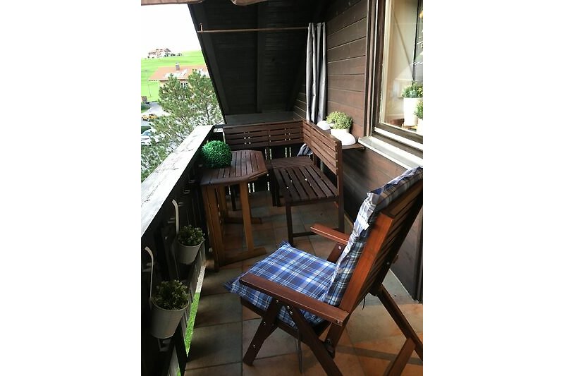Holzhaus mit Veranda, Tisch und Stühlen im Freien. Gemütliche Atmosphäre.