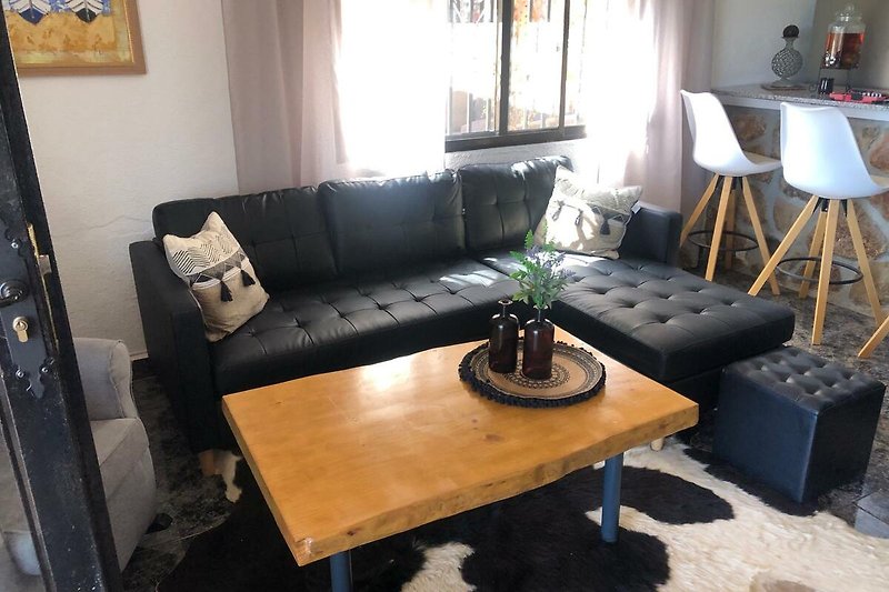 Wohnzimmer mit bequemer Couch, Tisch, Pflanze und Lampe. Gemütliche Einrichtung.