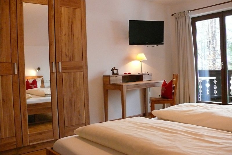 Schlafzimmer mit Holzmöbeln, Bett und Fenster. Gemütliche Inneneinrichtung. Holzboden und Lampen.