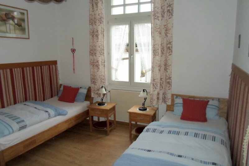 Schlafzimmer mit 2 Einzellbetten, Echtholzmöbeln und gemütlicher Beleuchtung.