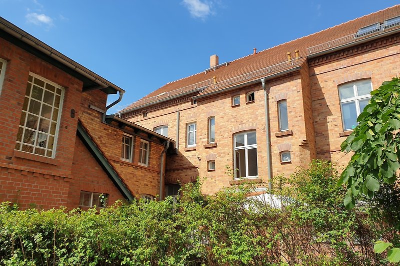 Historisches Haus mit Backsteinfassade, Sprossenfenstern und grünem Garten.