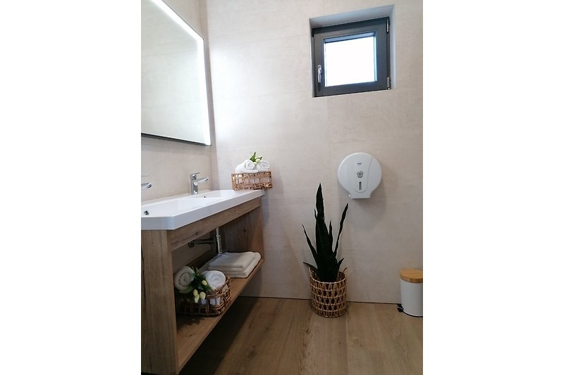 Modernes Badezimmer mit Blumen, Spiegel und Waschbecken.