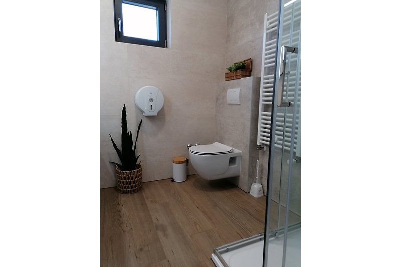 Modernes Badezimmer mit Fliesen, Fenster und Bilderrahmen.